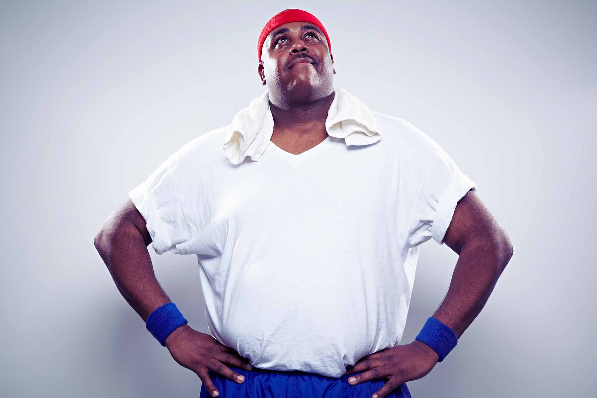 Overweight man in exercise clothing looking up post-workout.