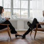 Man and woman sitting in chairs, the woman is laughing