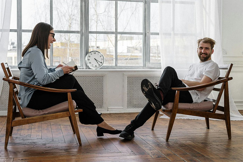 Man and woman sitting in chairs, the woman is laughing