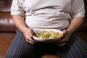 Close-up photo of an overweight man holding a bowl of food