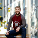 Man with a beard sitting on an urban park bench and laughing