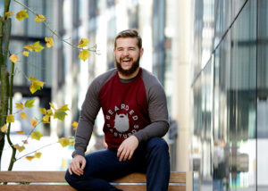 Man with a beard sitting on an urban park bench and laughing